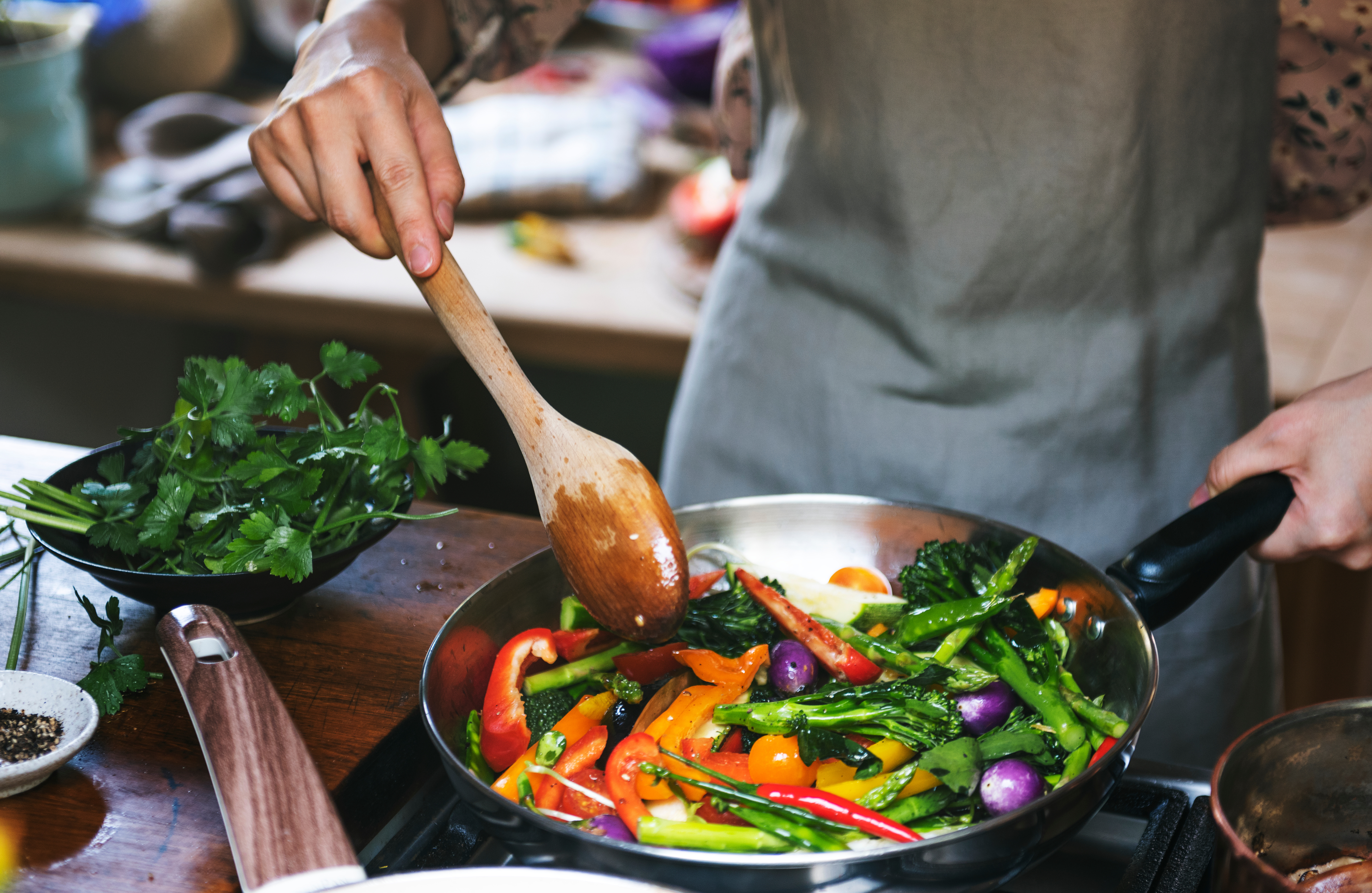 person cooking with vegetables in skillet