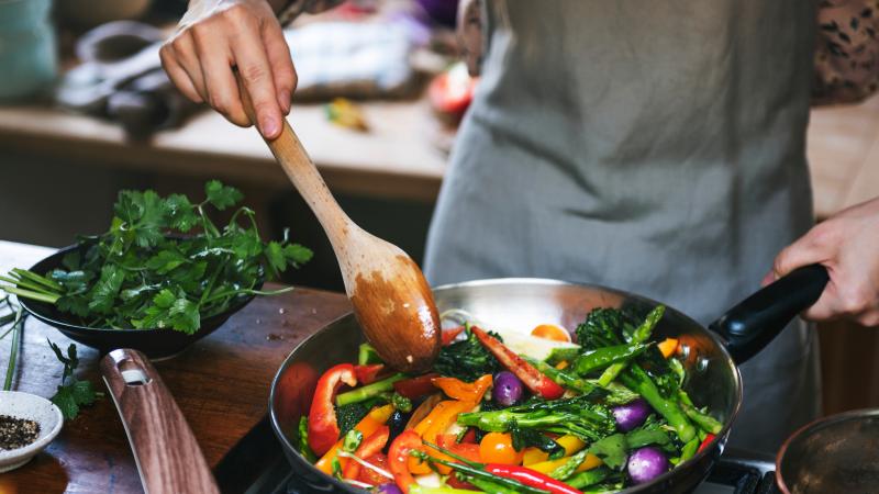 person cooking with vegetables in skillet